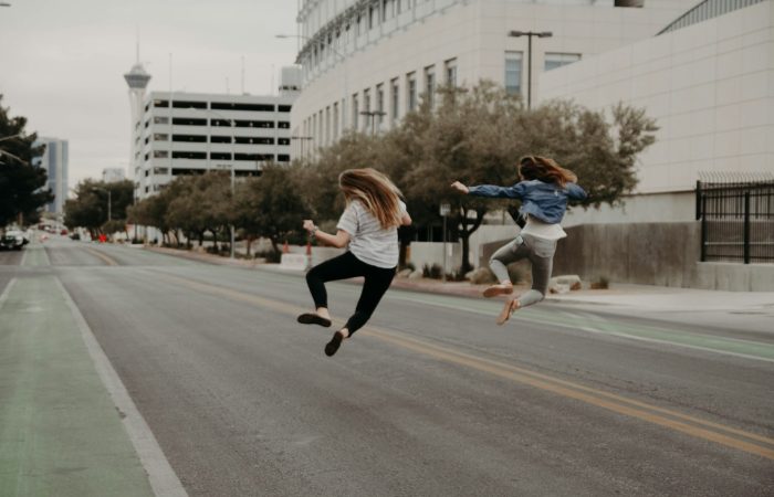 two woman jumping on the street during daytime