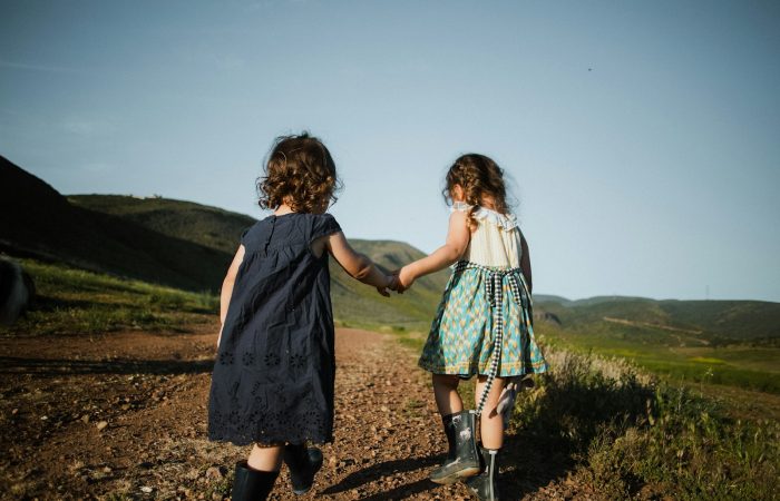 2 girls in blue dress standing on brown field during daytime