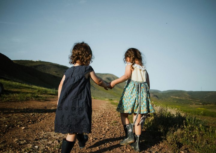 2 girls in blue dress standing on brown field during daytime